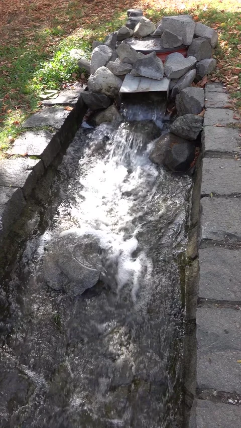 A stream emerging from underground in the city park Stock Footage 346391061