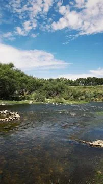 Stream falling between rocks, vegetation, sky with clouds Stock Photos
