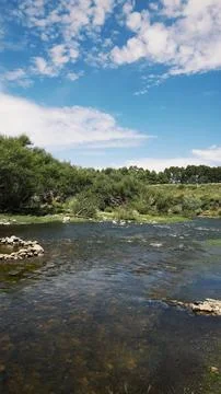 Stream falling between rocks, vegetation, sky with clouds Stock Photos