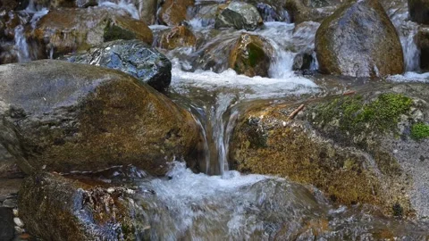 Stream falling over smooth dark rocks with tiny waterfall Video stock 296136728