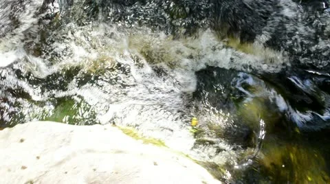 Stream flow between rocks and walk to rural homestead Stock Footage 20590205