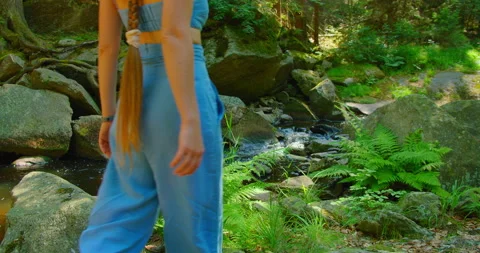 Stream flowing in forest slow motion. Long-haired attractive girl contemplates Stock Footage 205767551