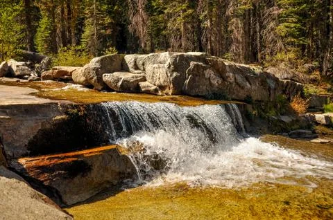 Stream flowing over a rocky ledge in the mountains Stock Photos
