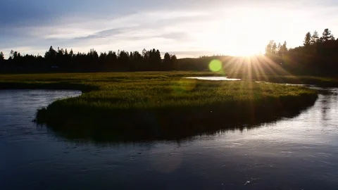 Stream flowing through a grassy field while sun sets Stock Footage 128205508
