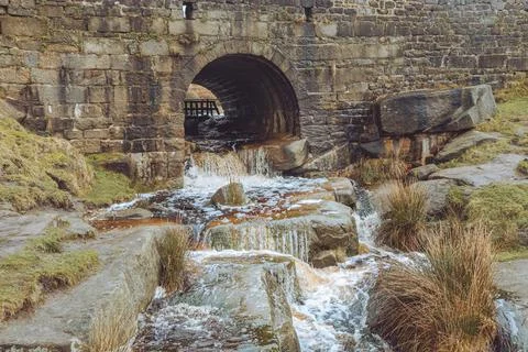 Stream flowing under a bridge and over rocks Foto stock