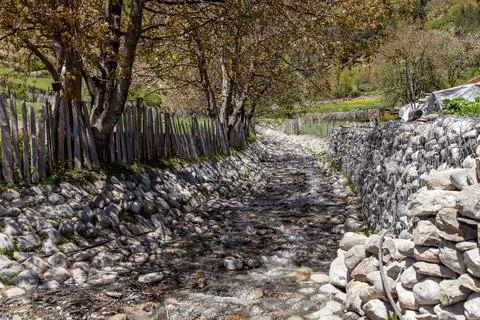 The stream flows along the road between fences Stock Photos