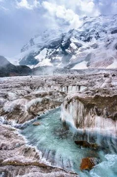 Stream flows down the glacier mountains in background. Stock Photos