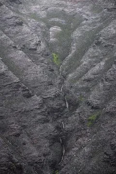 A stream flows down scorched hillsides after forest fires Stock Photos