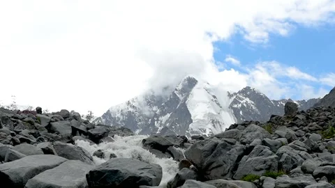 The stream flows from the glacier at the foot of the snowy mountains. Stock Footage 92670880