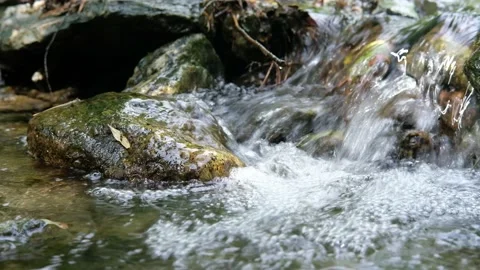 The stream flows over the stones forming a lot of air bubbles. Video stock 200140591