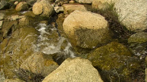 Stream flows through boulders Stock Footage 87318545