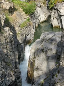 Stream flows through rocky gorge in a serene landscape during daylight Stock Photos