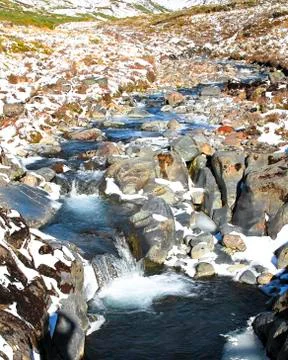 A stream flows through a snowy landscape in New Zealand Stock Photos