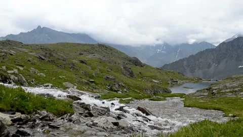 The stream flows into the valley high in the mountains Stock Footage 92670586