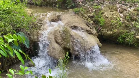A stream that forms a small waterfall in a farmer's field Stock Footage 234572663