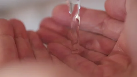 Stream of fresh drinking water pouring into human hands. Closeup Stock Footage 168482870