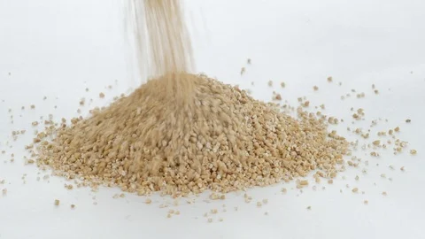 Stream of grains pour down onto a mound of stacked oats Stock Footage 91340620