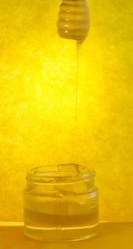 Stream of honey flows. Stream of pouring honey. Honey flowing from a wooden s 스톡 사진