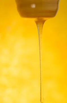 Stream of honey flows. Stream of pouring honey. Honey flowing from a wooden s Stock Photos