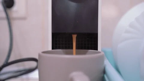 Stream of hot coffee is pouring into a cup from a compact capsule coffee machine Stock Footage 126653550
