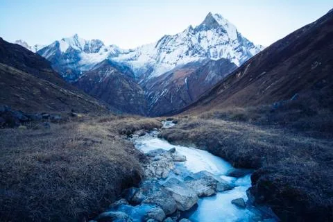 Stream with ice flowing down from the mountains, blue shade of the morning .. Stock Photos