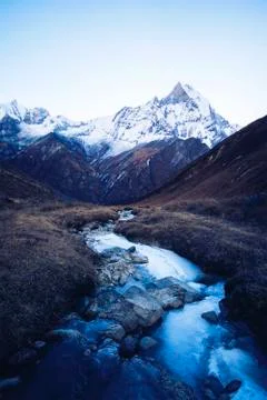 Stream with ice flowing down from the mountains, blue shade of the morning .. Stock Photos