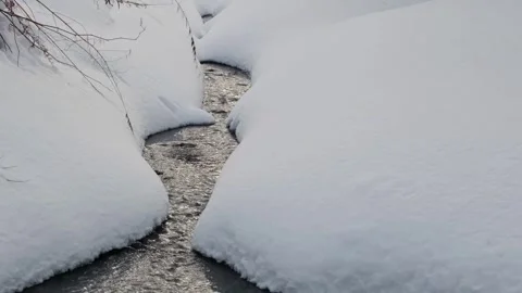 A stream makes its way through snow drifts. Stock Footage 300167049