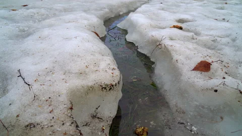 Stream of melt water over snow-covered ground 動画素材 236757642