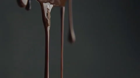 Stream of melted chocolate pouring on a black background. Slow motion video 120 Stock Footage 101480153