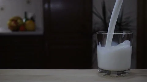 A stream of milk is poured in slow motion into a glass Stock Footage 129775318