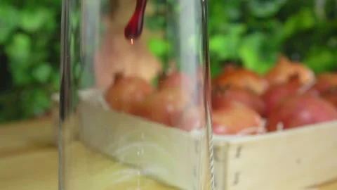 Stream of pomegranate juice flows into jug next to the box full of pomegranates Stock Footage 131017421