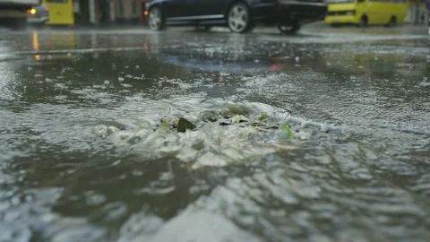 A stream of rainwater flows into the storm drain cars are driving in the Stock Footage 204948585
