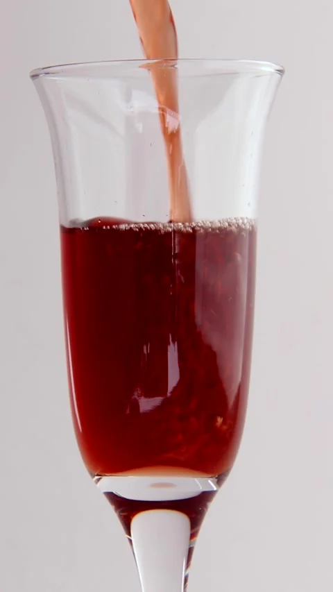 A stream of red wine pours into an empty glass on a white background. Stock Footage 277226756