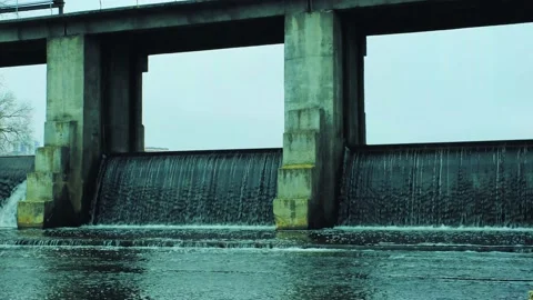 Stream of river water flowing from the city dam. The river flows through the dam Stock Footage 164375112