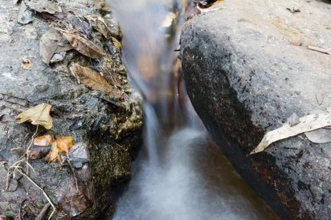Stream running between stones Stock Photos
