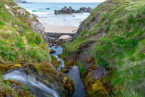 Stream running down through a creek to a beach Stock Photos