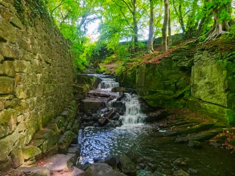 Stream running through an old mill race by a derelict mill 写真素材