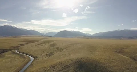Stream Runs Through Grassy Plains and Mountains, Aerial Drone Shot Stock Footage 281768328