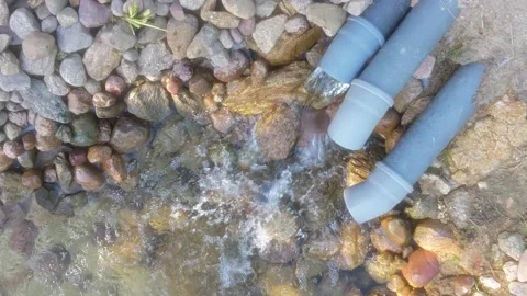 A stream of sewage flows out of a plastic sewer pipe into the river Stock Footage 249080946