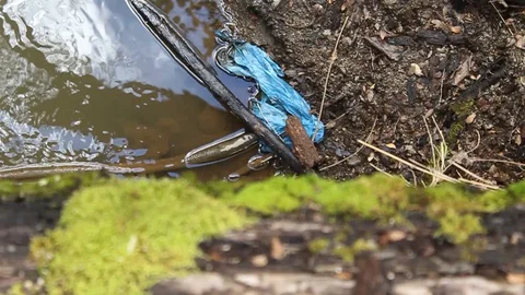 Stream shoreline littered with trash Stockbeeldmateriaal 128460492