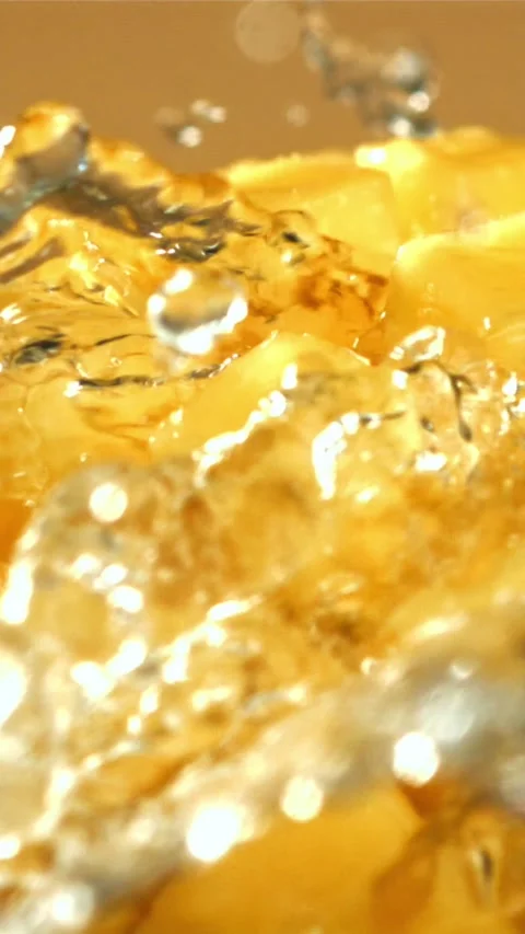 A stream of splashed water pours onto fresh mangoes. Filmed on a high-speed Stock Footage 335321288