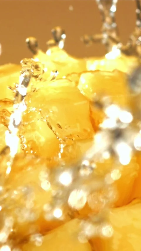 A stream of splashed water pours onto fresh mangoes. Filmed on a high-speed Stock Footage 335321776
