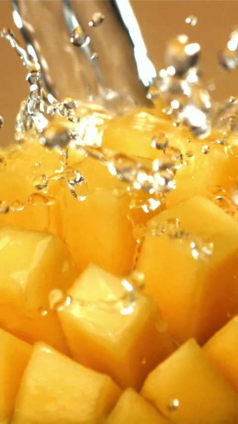 A stream of splashed water pours onto fresh mangoes. Filmed on a high-speed Stock Footage 335322594
