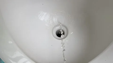 Stream of urine flowing into a white ceramic toilet bowl hole close up shot. 库存影片 280846471