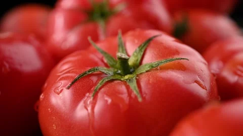 A stream of water and splashes fall on a red juicy tomato. Close-up. Stock Footage 271196349