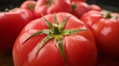 A stream of water and splashes fall on a red juicy tomato. Close-up. Stock Footage 271196528