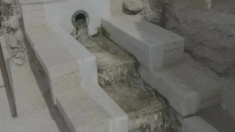 Stream of water circulating from a fountain through a white cement canal Stock Footage 185430752