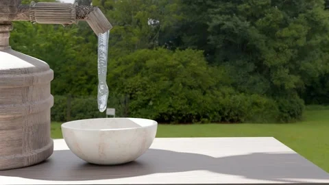 Stream of water coming out of a rustic wooden dispenser into a container vessel Stock Footage 204101611