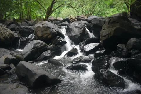 A stream of water falling between the rocks of a river Stock Photos