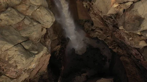 A Stream Of Water Falling Into a Deep Gorge, Canyon. Drone Video. Aerial View Stock Footage 128666704